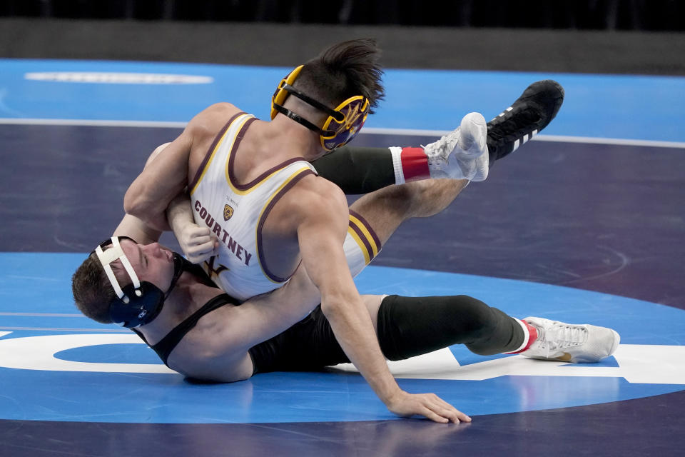 Iowa's Spencer Lee, bottom, takes on Arizona State's Brandon Courtney during their 125-pound match in the finals of the NCAA wrestling championships Saturday, March 20, 2021, in St. Louis. (AP Photo/Jeff Roberson)