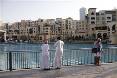 People wait by a waterfront in Dubai October 9, 2013. REUTERS/Ahmed Jadallah