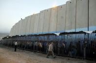 Palestinians wait to cross into Jerusalem next to Israel's controversial barrier at an Israeli checkpoint in the West Bank town of Bethlehem, in this July 7, 2013 file photo. REUTERS/Ammar Awad/Files