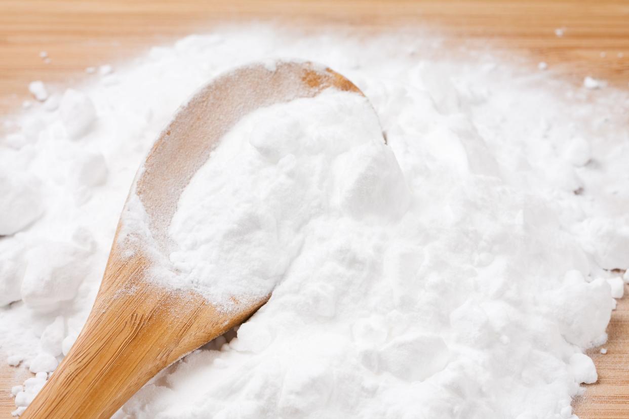 Large wooden spoon buried in baking soda on a wooden table