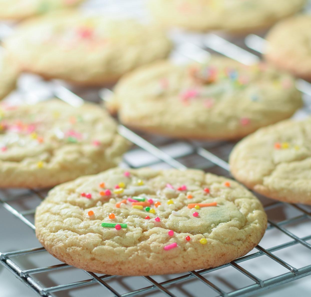 Freshly baked cookies on a rack with rainbow sprinkles.