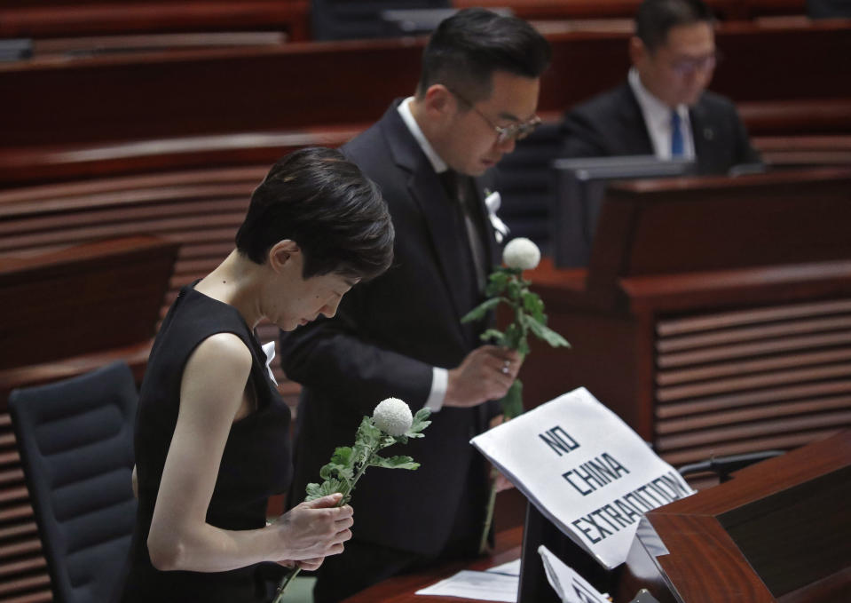 Pro-democracy lawmakers pay a silent tribute to the man who fell to his death on Saturday evening after hanging a protest banner on scaffolding on a shopping mall, at the Legislative Council in Hong Kong, Wednesday, June 19, 2019. Hong Kong lawmakers are meeting for the first time in a week, after massive protests over an extradition bill that eventually was suspended.(AP Photo/Vincent Yu)