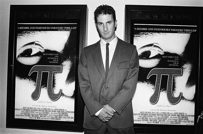 Black and White shot of Darren Aronofsky standing next to "Pi" movie posters