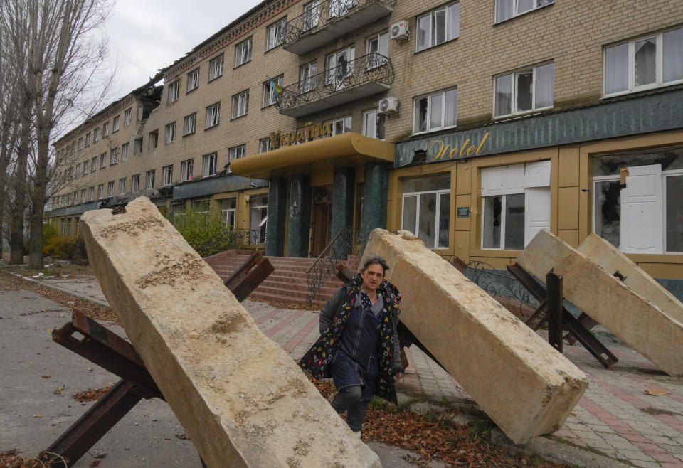 A woman walks past anti-tank hedgehogs, a city hotel in the background, in central Bakhmut, the site of the heaviest battle against the Russian troops in the Donetsk region, Ukraine, Friday, Oct. 28, 2022. (AP Photo/Efrem Lukatsky)