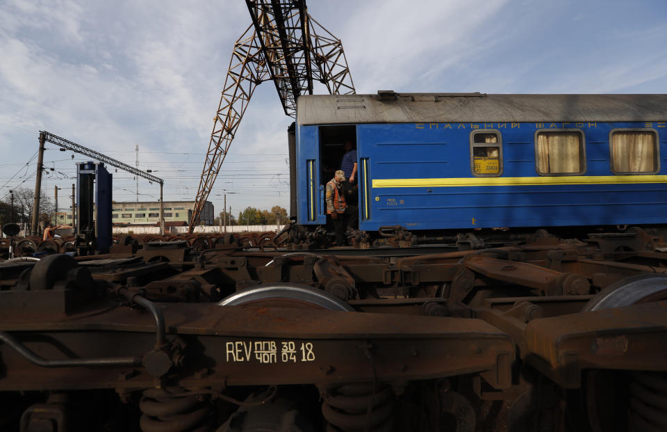 In this Thursday, Oct. 18, 2018 photograph, a worker descends from a carriage at a railroad track gauge changer in Chop, Ukraine. A new education law that could practically eliminate the use of Hungarian and other minority languages in schools after the 4th grade is just one of several issues threatening this community of 120,000 people. Many are worried that even as Ukraine strives to bring its laws and practices closer to European Union standards, its policies for minorities seem to be heading in a far more restrictive direction. (AP Photo/Laszlo Balogh)