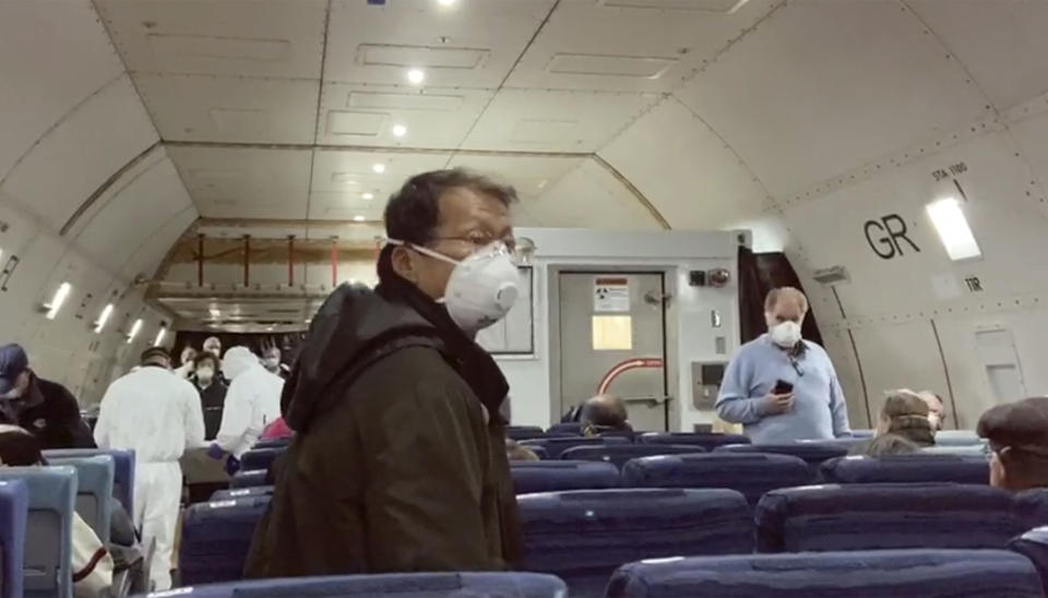 In this image from a video taken on Monday, Feb. 17, 2020, U.S. passengers who evacuated off the quarantined cruise ship the Diamond Princess, board a Kalitta Air plane bound for the U.S., at Haneda airport in Tokyo.(Cheryl and Paul Molesky via AP)