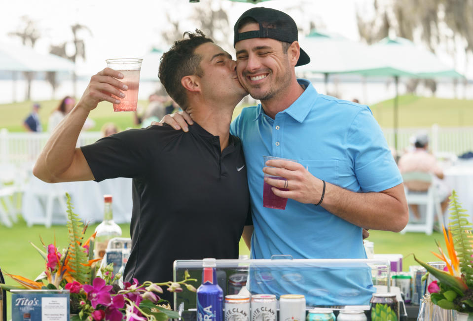 <p>Wells Adams plants a kiss on fellow <em>Bachelor</em> alumnus Ben Higgins behind a pop-up bar at the Hilton Grand Vacations Tournament of Champions in Orlando. </p>