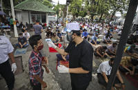 A mosque official takes the temperature reading of a man entering the Cut Meutia mosque to attend a Friday prayer amid concerns of coronavirus outbreak in Jakarta, Indonesia, Friday, June 5, 2020. Muslims in Indonesia's capital held their first communal Friday prayers as mosques closed by the coronavirus outbreak for nine weeks reopened at half capacity. (AP Photo/Dita Alangkara)