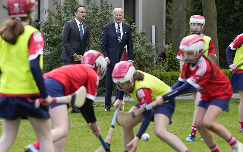 GIrls play hurling during a youth Gaelic sports demonstration as President Biden and Ireland's Taoiseach Leo Varadkar watch in the background