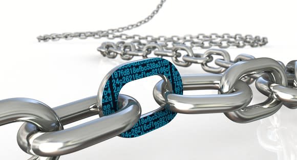 A long chain of steel links snaked across a white platform. Up close, one chain link is adorned with teal, hexadecimal numbers on a black background.