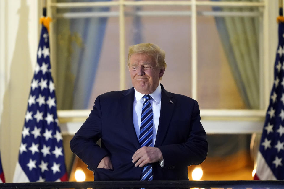 President Donald Trump puts his face mask into his pocket as he stands on the balcony outside of the Blue Room as returns to the White House Monday, Oct. 5, 2020, in Washington, after leaving Walter Reed National Military Medical Center, in Bethesda, Md. Trump announced he tested positive for COVID-19 on Oct. 2. (AP Photo/Alex Brandon)