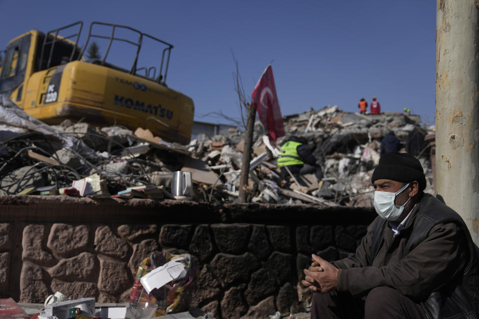 A man sits next to the rubble of destroyed buildings in Adiyaman, southern Turkey, Sunday, Feb. 12, 2023. Six days after earthquakes in Syria and Turkey killed tens of thousands, sorrow and disbelief are turning to anger and tension over a sense that there has been an ineffective, unfair and disproportionate response to the historic disaster. (AP Photo/Khalil Hamra)