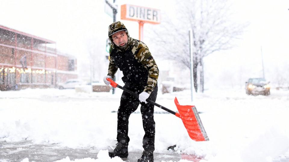 PHOTO: Jorge Perera sweeps snow at the corner of Broadway and 1st Ave. in Denver, Colorado, March 14, 2024.  (Hyoung Chang/Denver Post via Getty Images)