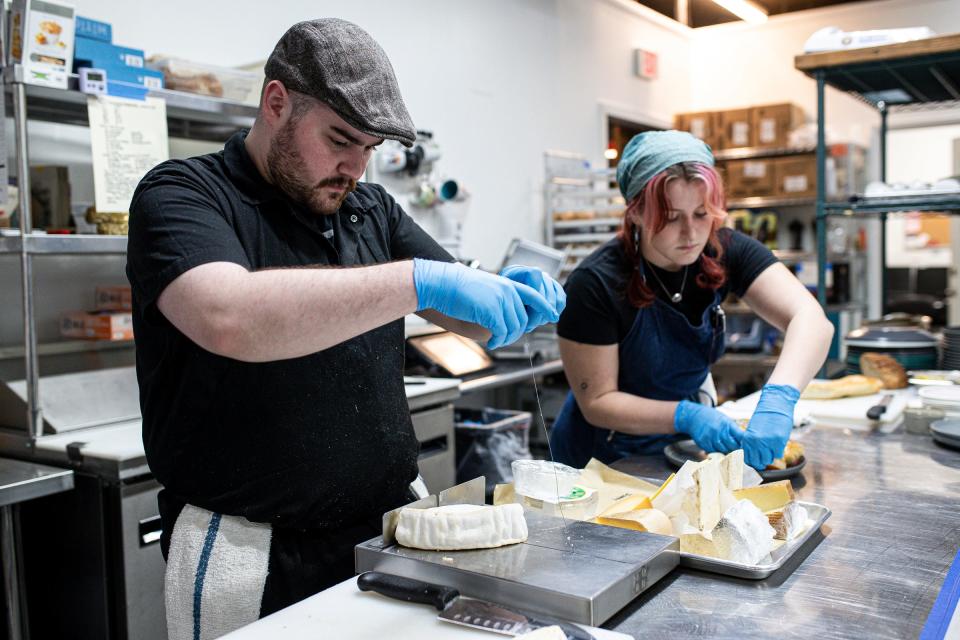 Cook Reece Sharples slices cheese as Anna Calhoun prepares a cheese and meat charcuterie board at the Rind in Berkley.