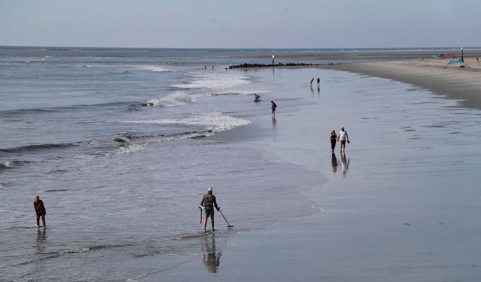Visitors stroll along the beach at Tybee Island near the pier.