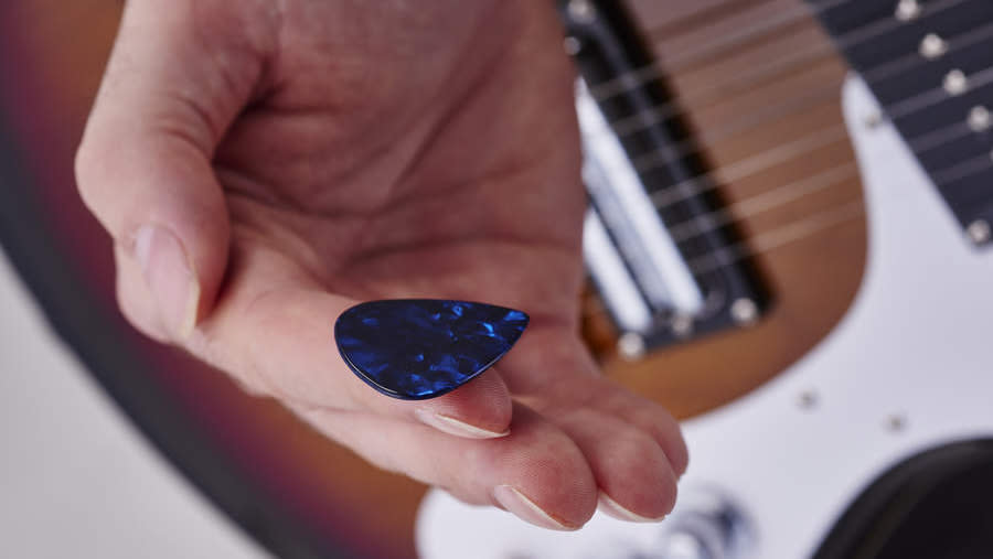  Hand holding a guitar pick . 