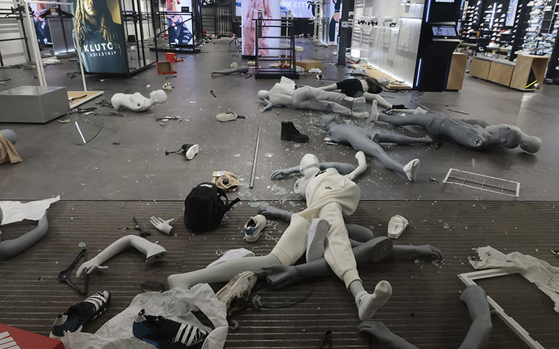 Mannequins appear strewn across a shop floor amid broken glass, shooes and other debris.