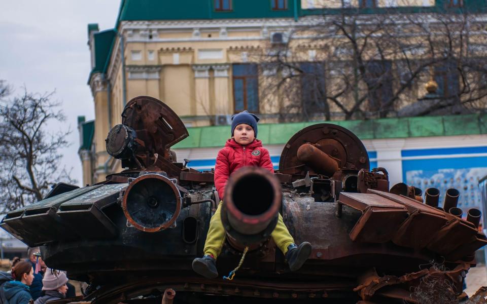  With a defiant attitude, a child sits on the canon of a tank destroyed by Ukrainian armed forces in Kyiv - ZUMA Press, Inc. / Alamy Live News/https://www.alamy.com