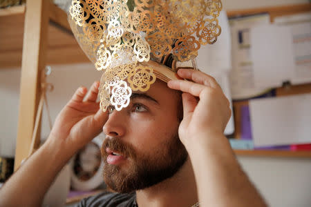 Syrian migrant Haidar Darwish tries on a head ornament in his flat in Berlin, Germany, July 13, 2018. REUTERS/Alessia Cocca