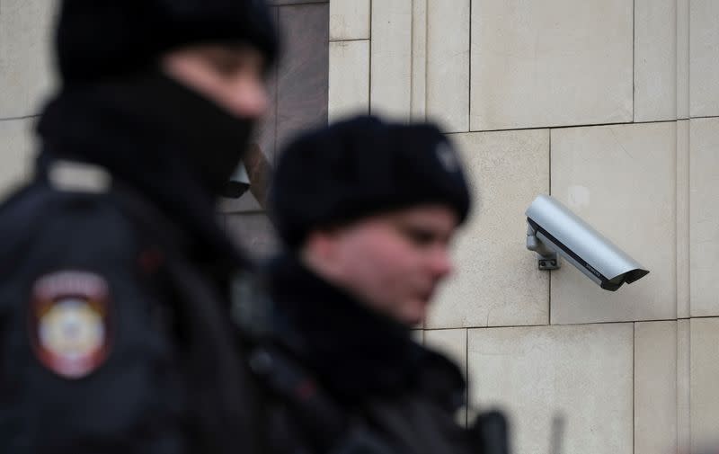 FILE PHOTO: Police officers walk past a CCTV camera in central Moscow