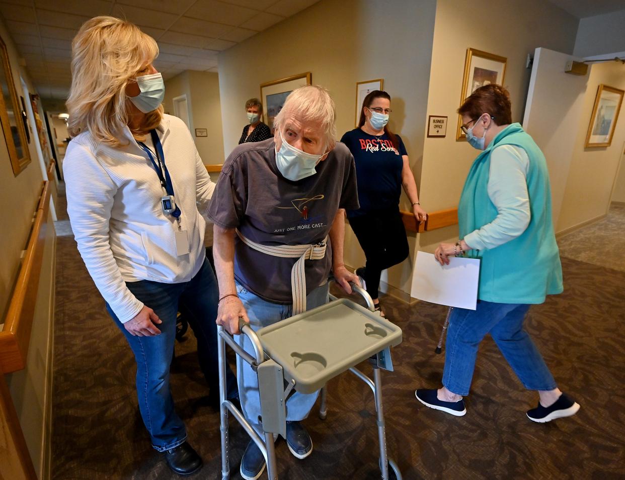 Christopher House resident Donald Brickman, 88, walks in the hallway with Debbie Sherman, left.