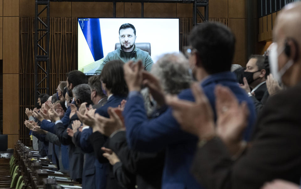 Members of Canada’s Parliament applaud as Ukrainian President Volodymyr Zelensky is shown on a video screen.