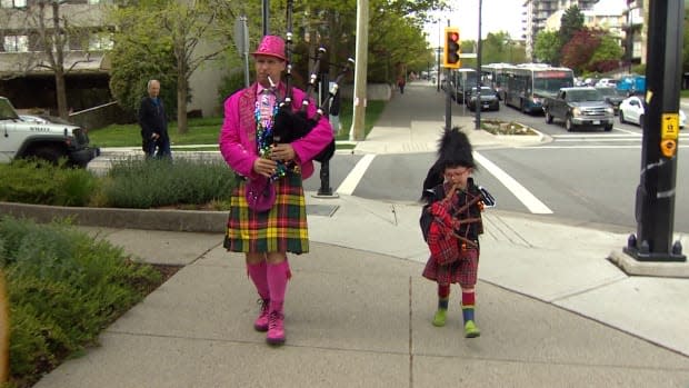 Frankie Whelan, 4, plays his set of bagpipes alongside his hero, Frank Wimberley, also known as the Pink Pied Piper, in North Vancouver, B.C. They meet every Friday and walk down Lonsdale Avenue playing the pipes together. (Kevin Li/CBC - image credit)