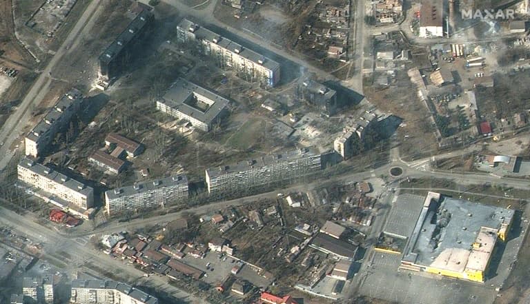 Cette photo satellite prise par la société Maxar satelitte le 18 mars 2022 montre des bâtiments d'habitation et des commerces de Marioupol (Ukraine) en flammes et très endommagés - - © 2019 AFP