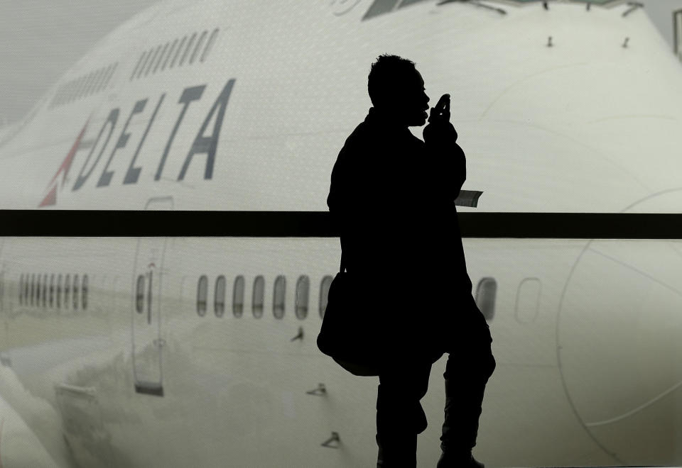 FILE - In this Oct. 29, 2012, file photo, a traveler on Delta Airlines waits for her flight in Detroit. For the past decade fliers haven't been able to use electronic devices while planes are below 10,000 feet because they might interfere with cockpit instrument, but the Federal Aviation Administration declared Thursday Nov. 21, 2013, that interference isn't a concern anymore. (AP Photo/Charlie Riedel, File)