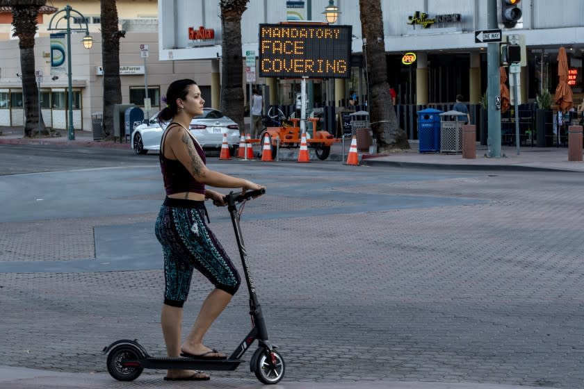 PALM SPRINGS, CA - JULY 16, 2020: A woman on a scooter ignores the mandatory face coverings order in downtown Palm Springs on July 16, 2020 in Riverside County, California. Riverside County is experiencing a surge in COVID-19 cases.(Gina Ferazzi / Los Angeles Times)