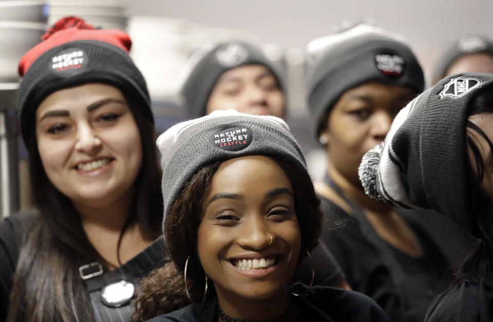 Tavern workers sport hockey-themed caps ahead of an expected announcement of an NHL expansion hockey team in Seattle, at a gathering Tuesday, Dec. 4, 2018, in Seattle. The NHL Board of Governors met in Georgia and is expected to give final approval to Seattle's bid to add the league's 32nd team. Play would be expected to begin in the 2021-22 season. (AP Photo/Elaine Thompson)