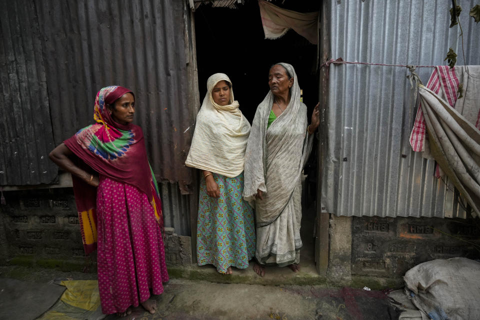 Subur Banoo, 60, right, wife of late Faizul Ali, and her two daughter-in-laws stand outside their house in Bahari, north eastern Assam state, India, April 16, 2023. Ali was sent to a detention center after being declared a “foreigner” in late 2015, and was released on bail in 2019. He died in March, leaving behind his wife, a mentally ill son, two daughter-in-laws and their children. They all live in a single room house made of corrugated tin in this Muslim majority village. All have been declared “foreigners.” (AP Photo/Anupam Nath)