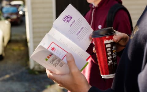 A customer reads a pamphlet on cannabis products while waiting in line outside of a Nova Scotia Liquor Corp. - Credit: Dean Casavechia/Bloomberg