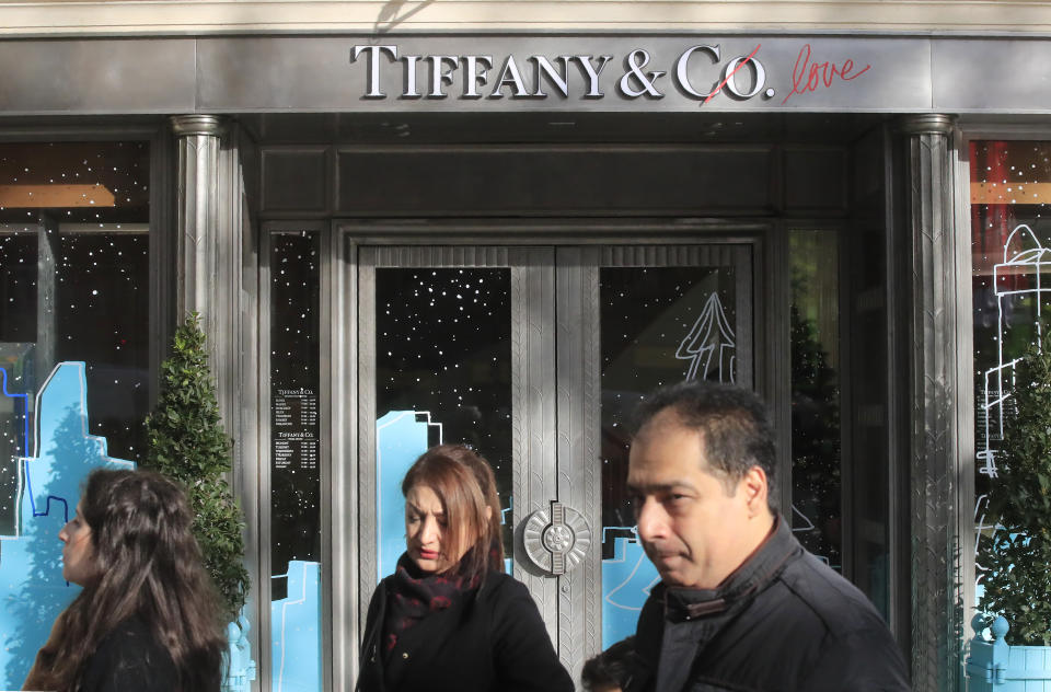 FILE - In this Nov.25, 2019 file photo, people walk past a Tiffany jeweler shop on the Champs Elysees avenue in Paris. LVMH is ending its monthslong pursuit of luxury jewelry retailer Tiffany & Co., citing in part the impact of proposed tariffs on French goods. The Paris-based conglomerate said that it needs more time to assess the impact of U.S. tariffs on French goods and cannot close the deal before year-end. (AP Photo/Michel Euler, File)