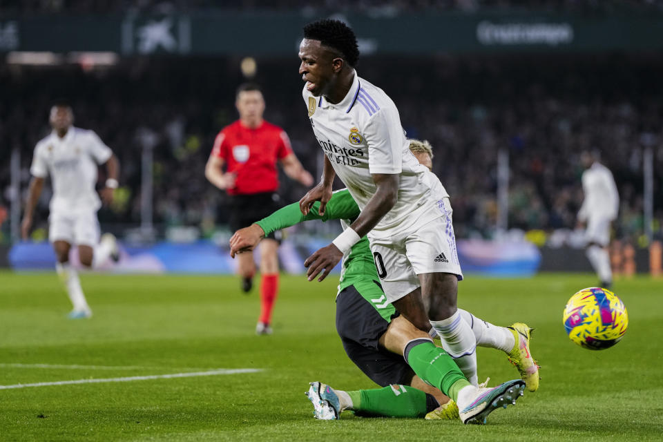 Vinicius Junior (primer plano) del Real Madrid trata de superar a Germán Pezzella del Betis en la Liga española, el domingo 5 de marzo de 2023. (AP Foto/José Bretón)