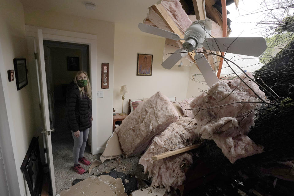 Amy Lilly peers into the room damaged by a tree limb that crashed into her house during a storm in Sacramento, Calif., Wednesday, Jan. 27 2021. High-winds and rain pelted the region causing damage throughout the area. (AP Photo/Rich Pedroncelli)