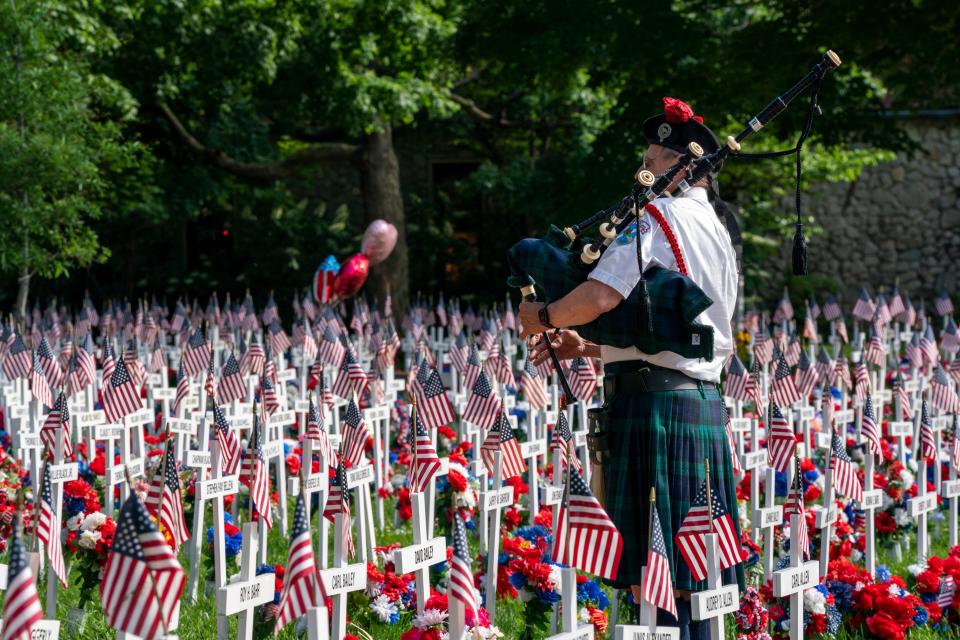 Seton Norris with Kyilindi Pipe and Drums plays the bagpipes surrounded by the 6,160 crosses on display for Memorial Day in Henderson's Central Park Thursday, May 16, 2024.