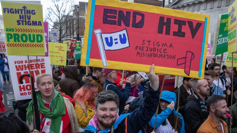 A crowd of people marches down a street with signs that read 