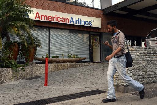 Un hombre camina por enfrente de una oficina de venta de boletos de la aerolínea estadounidense American Airlines, en Caracas, Venezuela, el 17 de junio de 2014. La aerolínea reducirá a partir de julio la frecuencia de sus vuelos a Venezuela, tras no llegar a un acuerdo con el gobierno para cobrar una millonaria deuda. (AFP | Leo Ramirez )