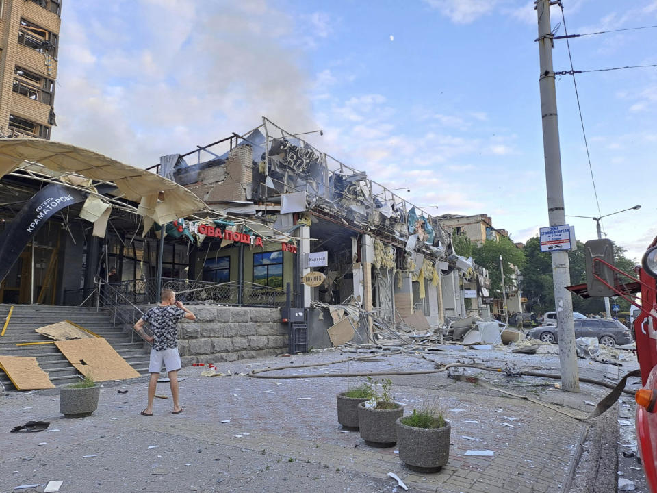 In this photo provided by the Ukrainian Donetsk Regional Administration, a man stands on a street in front of a shop and restaurant RIA Pizza destroyed by a Russian attack in Kramatorsk, Ukraine, Tuesday, June 27, 2023. (Ukrainian Donetsk Regional Administration via AP)