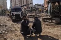 Two men watch the firefighters and rescue teams as they search for people in a destroyed building, in Adana, southern Turkey, Wednesday, Feb. 8, 2023. Nearly two days after the magnitude 7.8 quake struck southeastern Turkey and northern Syria, thinly stretched rescue teams work to pull more people from the rubble of thousands of buildings. (AP Photo/Petros Giannakouris)