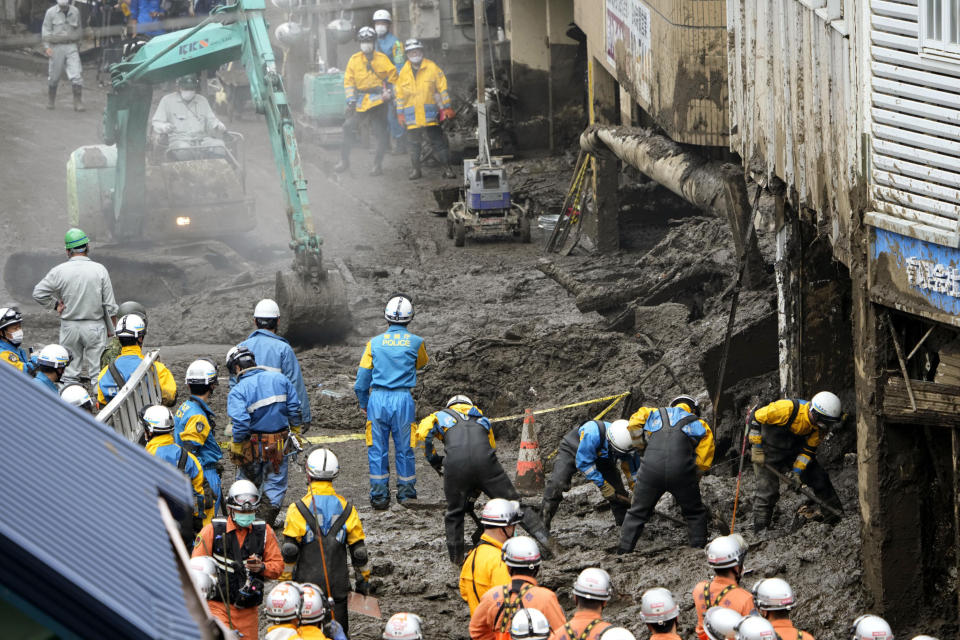 Police officers, in blue, and firefighters, in orange, continue a search operation for missing people at the site of a mudslide in Atami, southwest of Tokyo Tuesday, July 6, 2021. Rescue workers struggled with sticky mud and risks of more mudslides Tuesday as they searched for people may have been trapped after a torrent of mud that ripped through a seaside hot springs resort. (Kyodo News via AP)