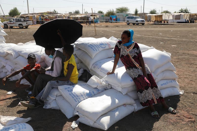 Ethiopian refugees sit on bags of food aid at the Village 8 refugees transit camp, which houses Ethiopian refugees fleeing the fighting in the Tigray region, near the Sudan-Ethiopia border