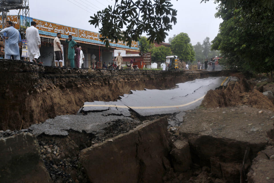 People stand beside a damaged portion of a road caused by a powerful earthquake in Jatla near Mirpur, northeastern Pakistan, Wednesday, Sept. 25, 2019. Mourners were burying their dear ones in Pakistan-held Kashmir where a powerful earthquake struck a day before. (AP Photo/Anjum Naveed)