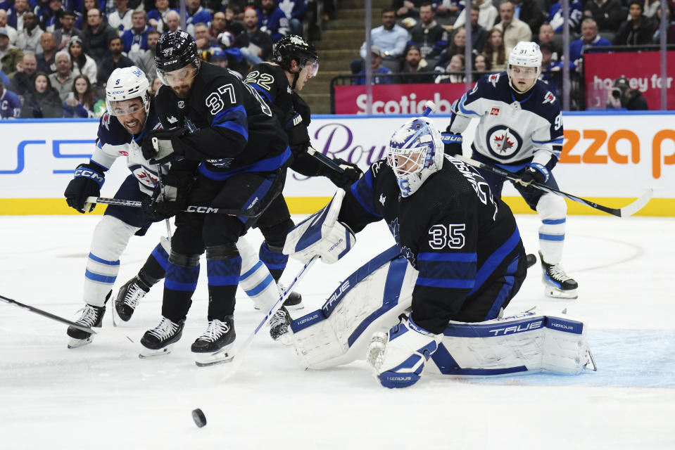 Toronto Maple Leafs goaltender Ilya Samsonov (35) makes a save as Winnipeg Jets forward Alex Iafallo (9) and Maple Leafs defenseman Timothy Liljegren (37) battle during the first period of an NHL hockey game in Toronto, Wednesday, Jan. 24, 2024. (Nathan Denette/The Canadian Press via AP)