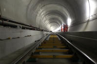 Journalists stand beside rail tracks at the construction site in the NEAT Gotthard Base tunnel near Sedrun April 2, 2013. Crossing the Alps, the world's longest train tunnel should become operational at the end of 2016. The project consists of two parallel single track tunnels, each of a length of 57 km