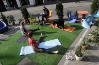 People practice yoga during the PARK(ing) Day event in Riga, September 20, 2013. The event aims to transform metered parking spaces into temporary public places to call attention to the need for more urban open spaces and discuss the creation and allocation of public spaces, according to organizers. (REUTERS/Ints Kalnins)