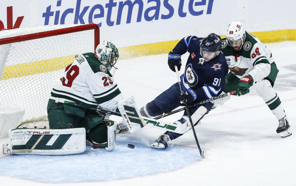 Minnesota Wild goaltender Marc-Andre Fleury (29) saves a shot by Winnipeg Jets' Cole Perfetti (91) as Wild's Frederick Gaudreau (89) defends during the third period of an NHL hockey game, Saturday, Dec. 30, 2023 in Winnipeg, Manitoba. (John Woods/The Canadian Press via AP)