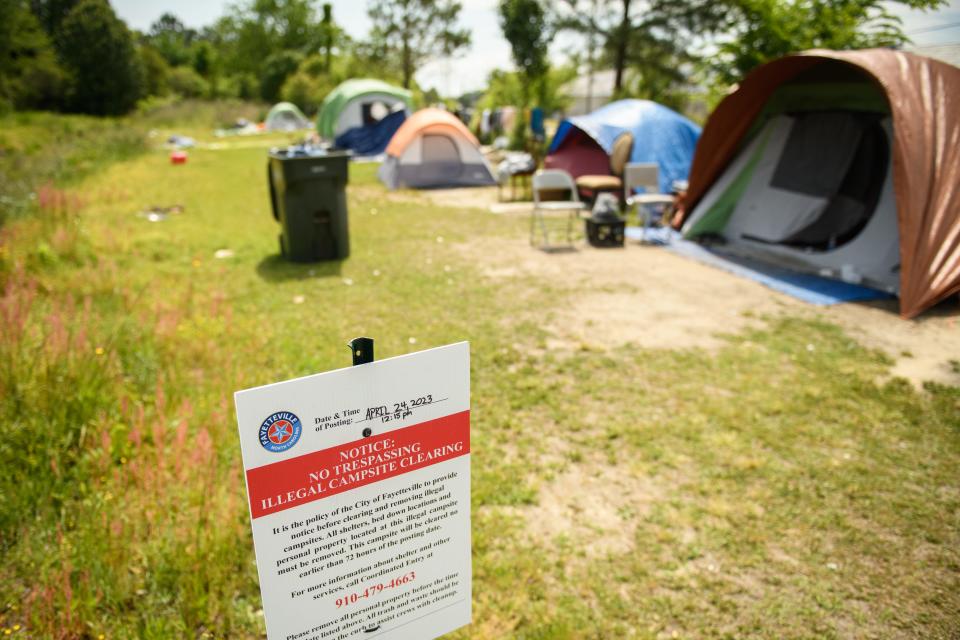 A sign from the city of Fayetteville is posted at a homeless encampment at Gillespie Street and Martin Luther King Jr. Freeway. The sign states that the encampment will be cleared in the near future.