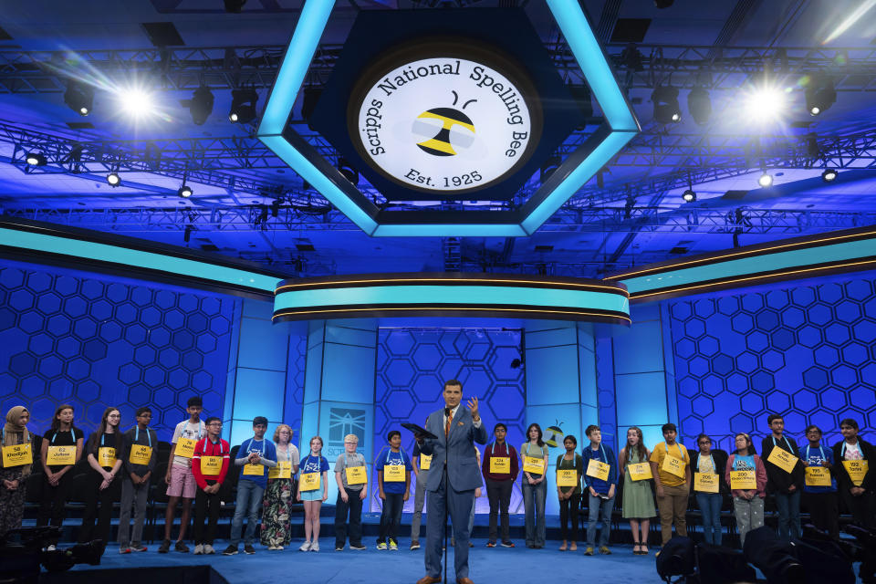 Broadcast analyst Paul Loeffer, center, presents the semifinalists during the Scripps National Spelling Bee, Wednesday, May 31, 2023, in Oxon Hill, Md. (AP Photo/Nathan Howard)